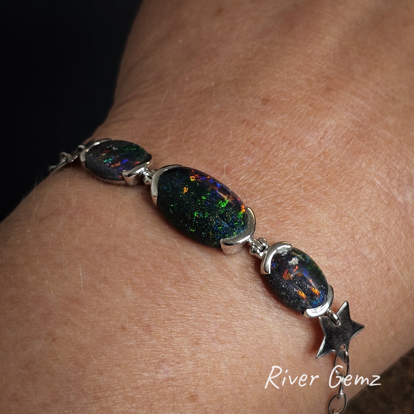 Tri-opal bracelet with silver accents on a wrist, branded 'River Gemz'.
