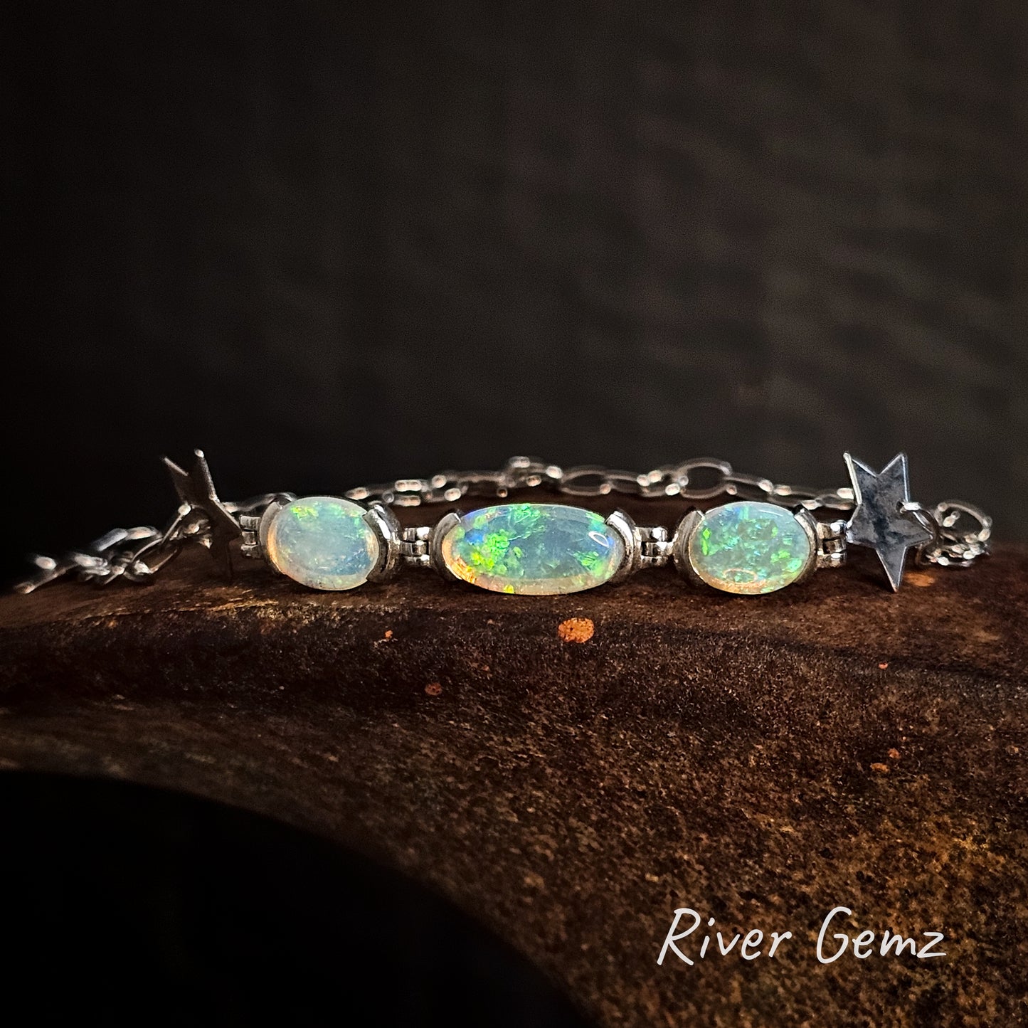 Three crystal opals partial besel set in silver bracelet with stars part of the chain link.