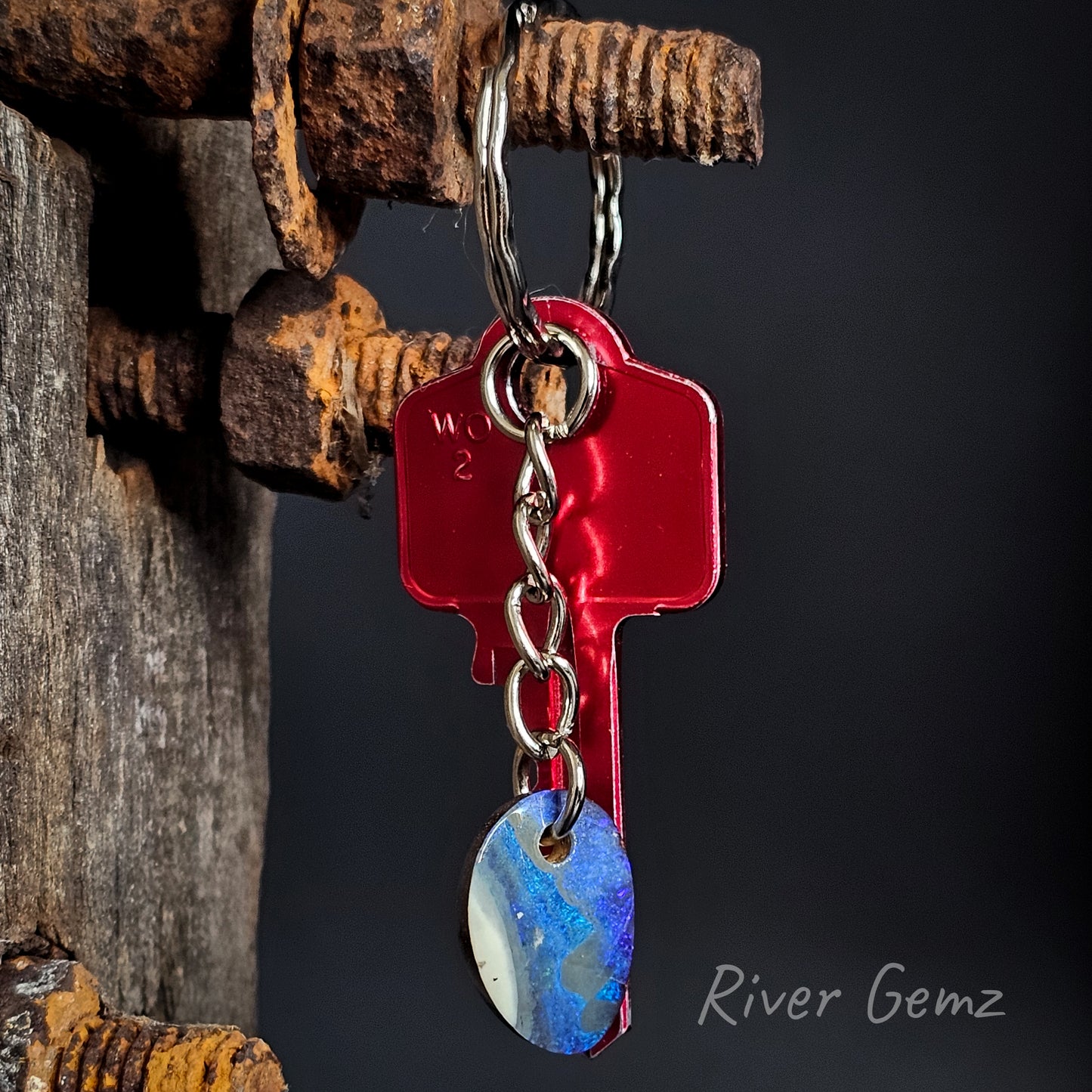 Blue and white boulder opal on a key chain on a dark background.