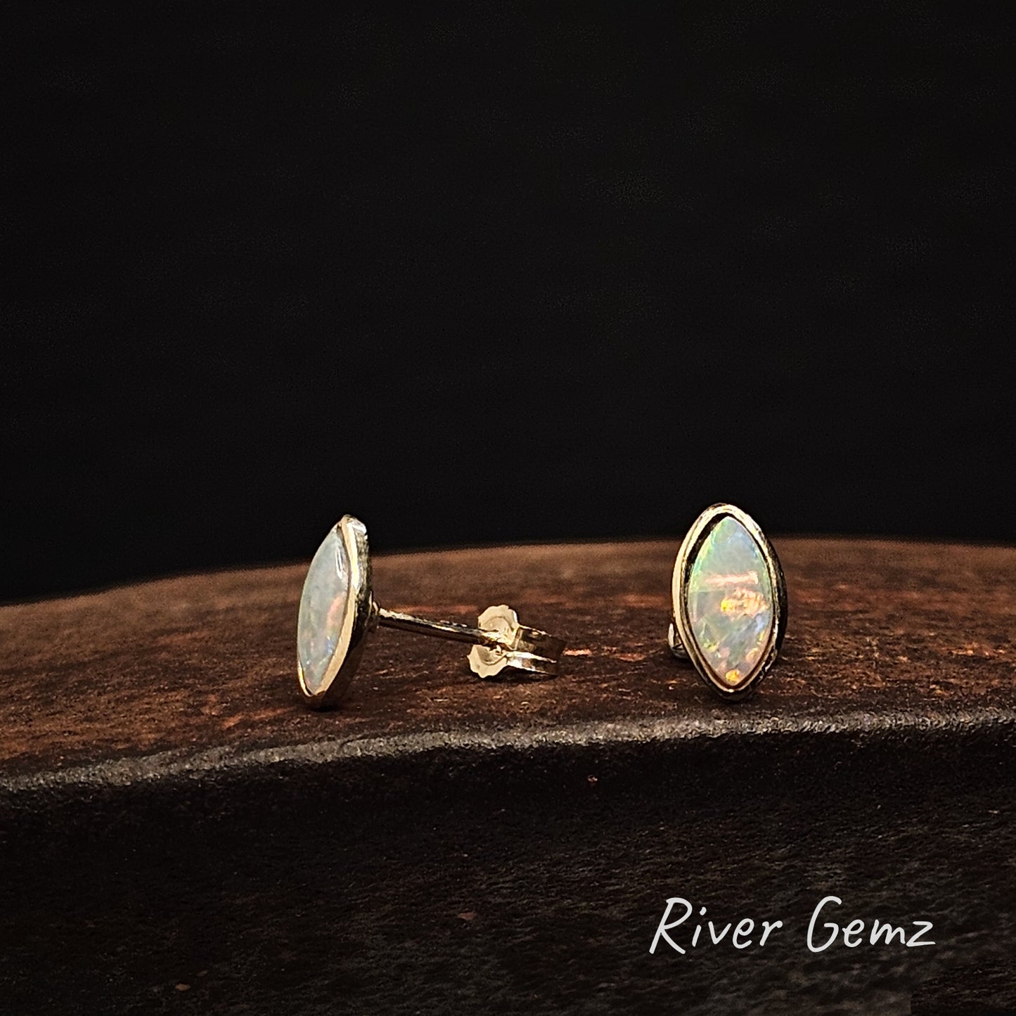 Left earring side view and right front view in gold opal earrings against a dark background with 'River Gemz' branding.