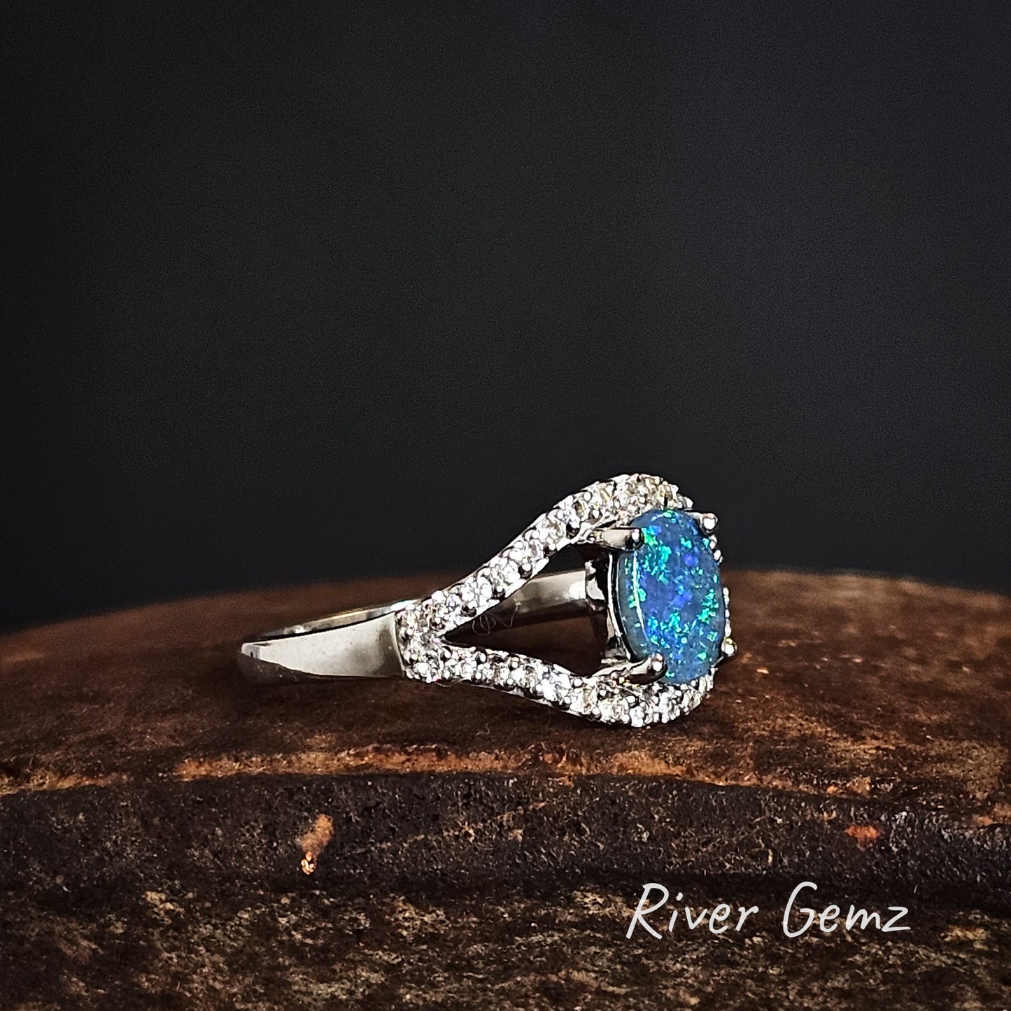 Ring with a blue gemstone on a dark background, featuring the brand 'River Gemz'.