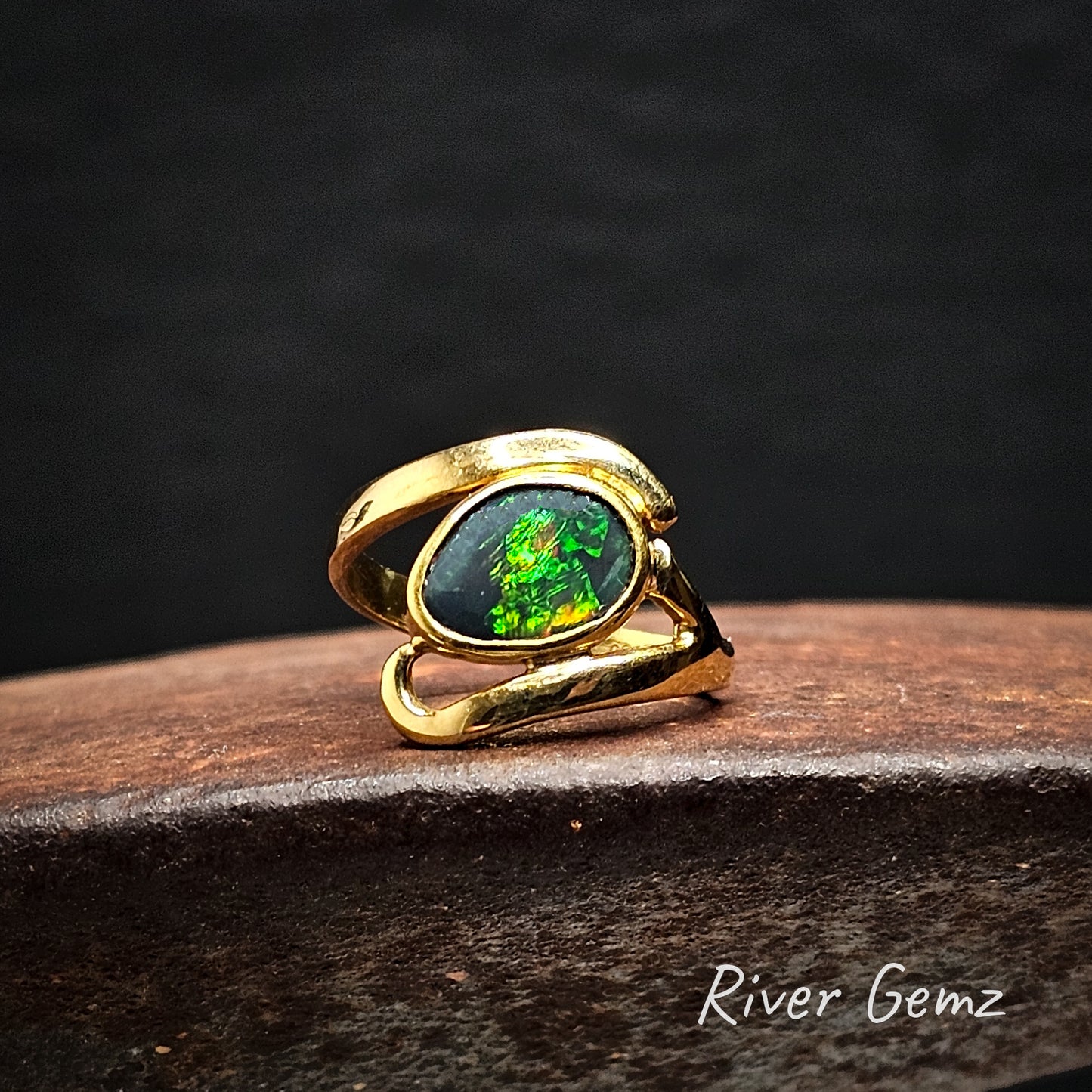Gold ring with a green gemstone on a dark background, branded 'River Gemz'.