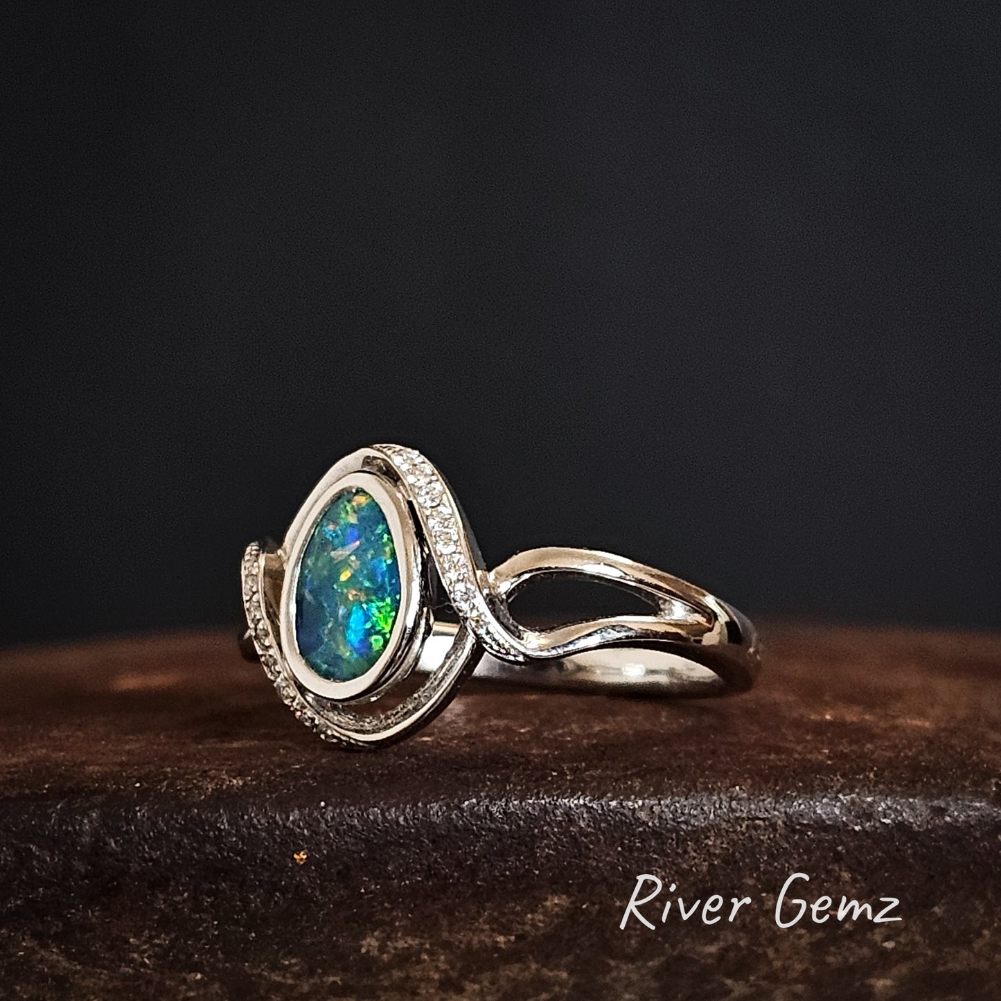 Teardrop shaped black opal besel set in modern design white gold ring.