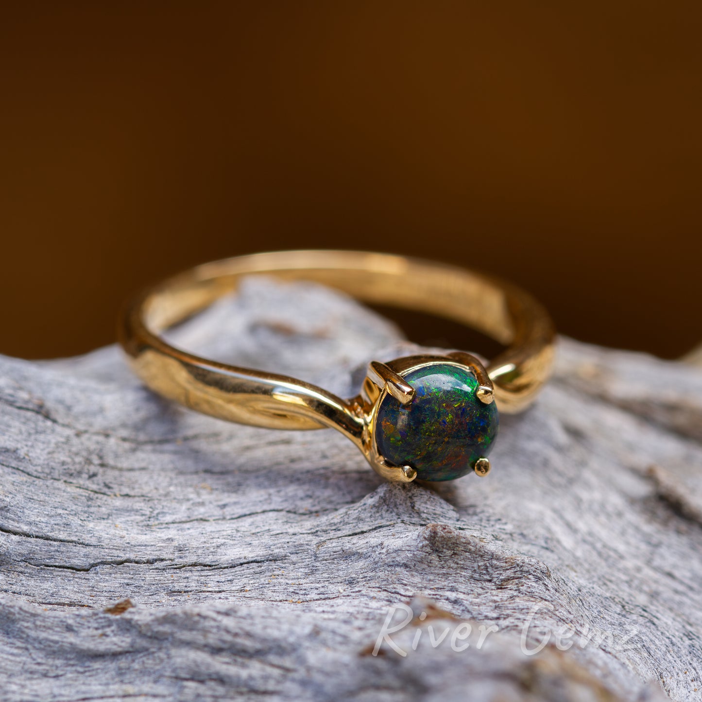 Magnificent array of colours embody the black opal claw set in the narrow shank yellow gold ring.