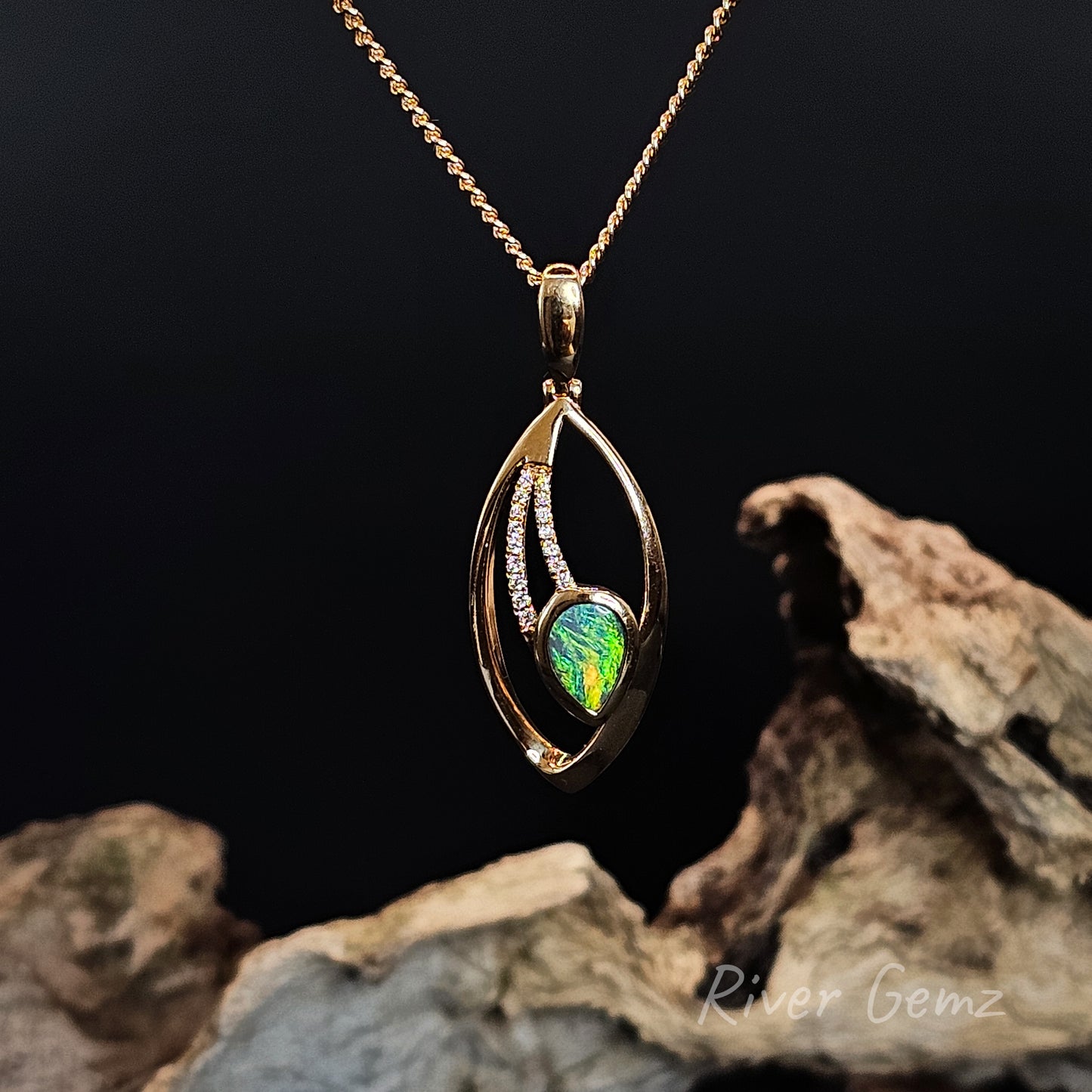 Gold pendant with a bright green opal and string of white diamonds on a dark background