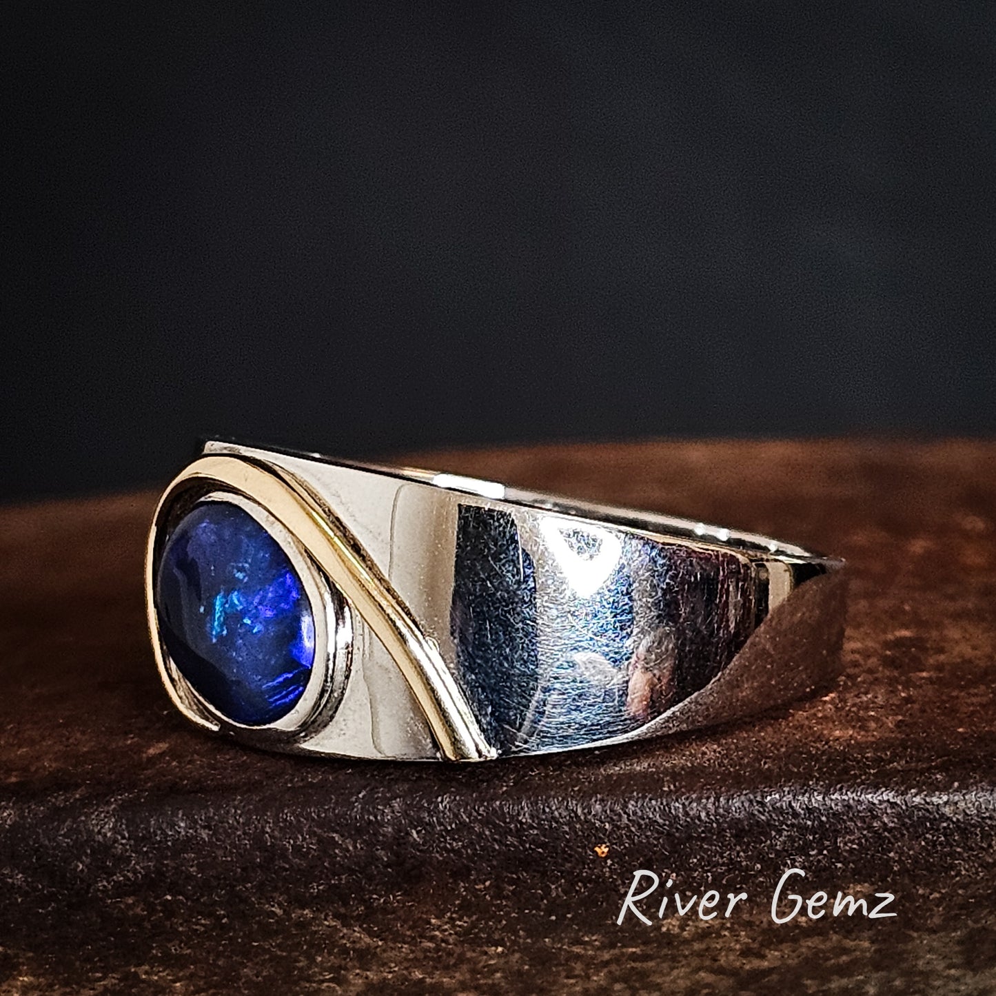 Gold arc over the oval shaped black opal at the face of the sterling silver ring.