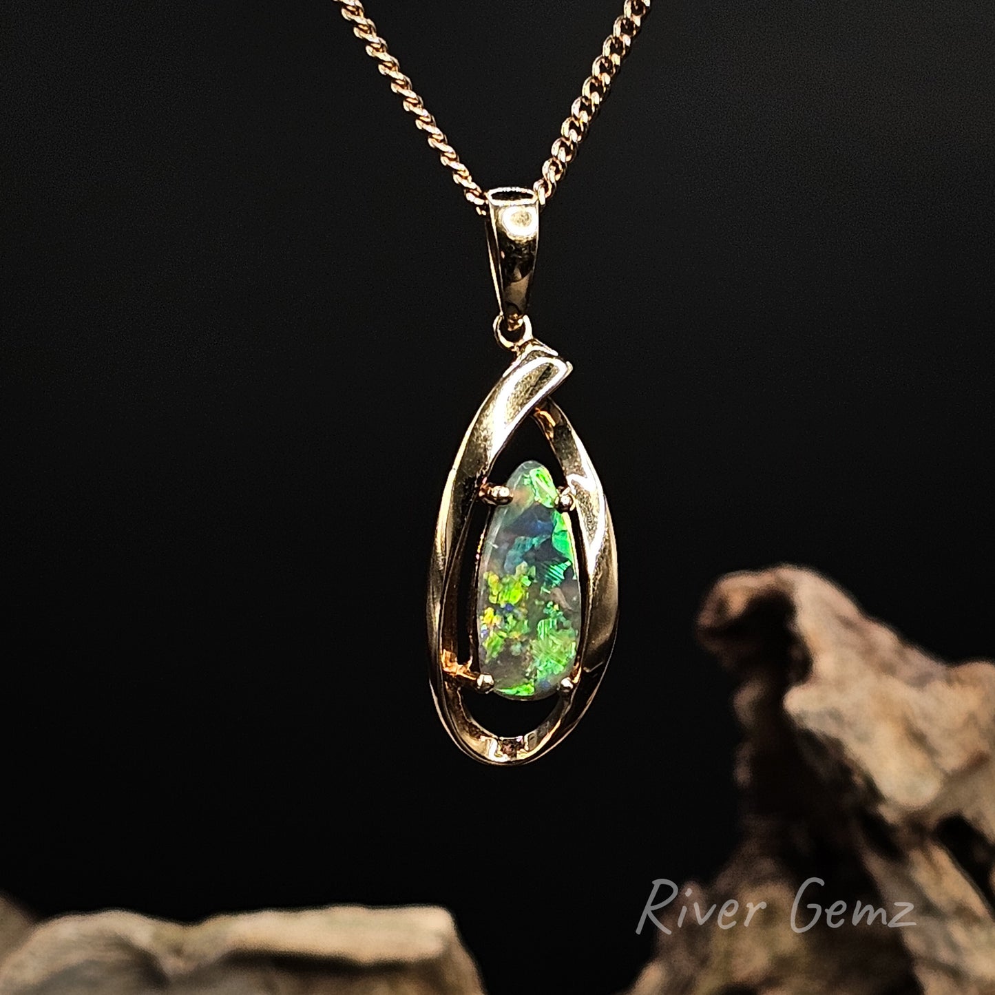 Opal pendant in gold setting on a dark background with 'River Gemz' branding.