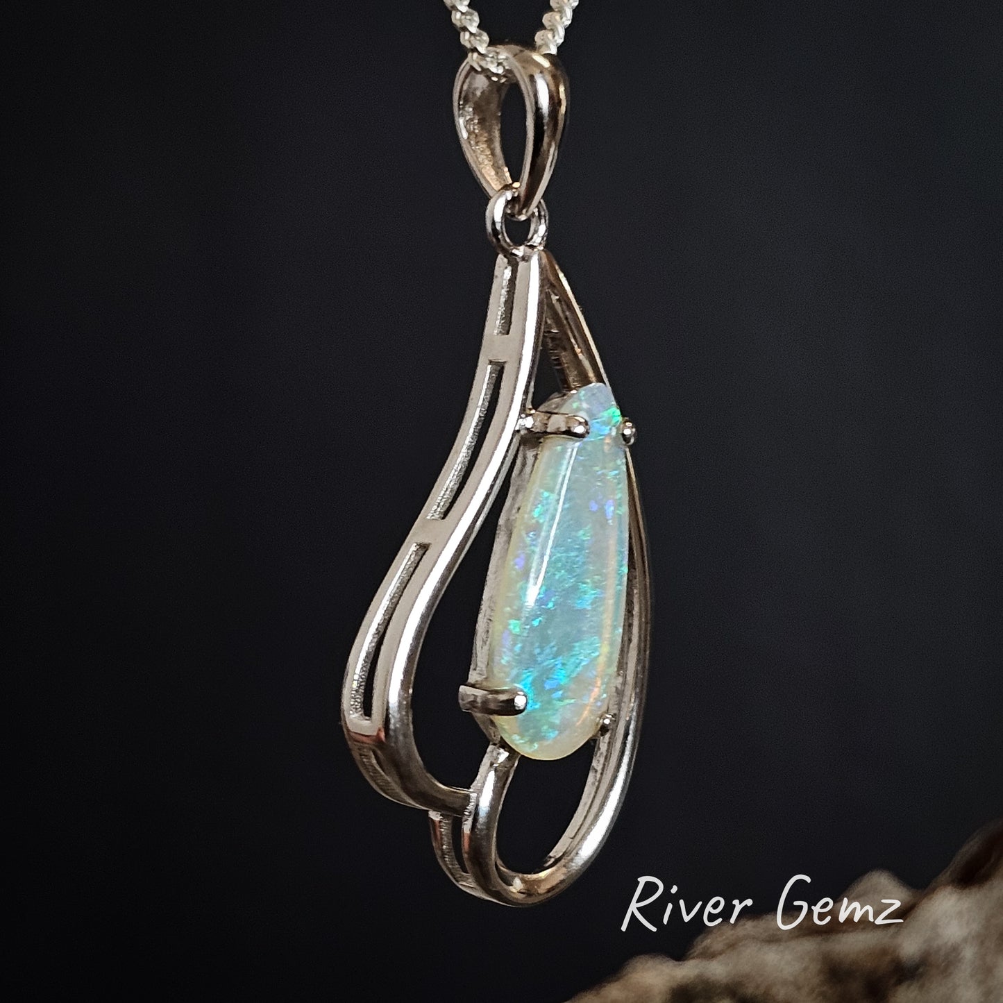Skewed view of the light green crystal opal claw set in sterling silver necklace with large tapered bail.