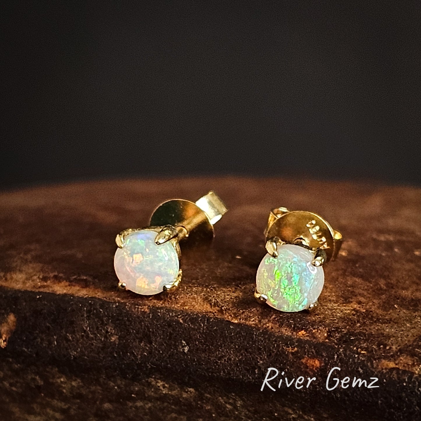 Crystal opal in yellow gold earrings on a dark background with 'River Gemz' branding.