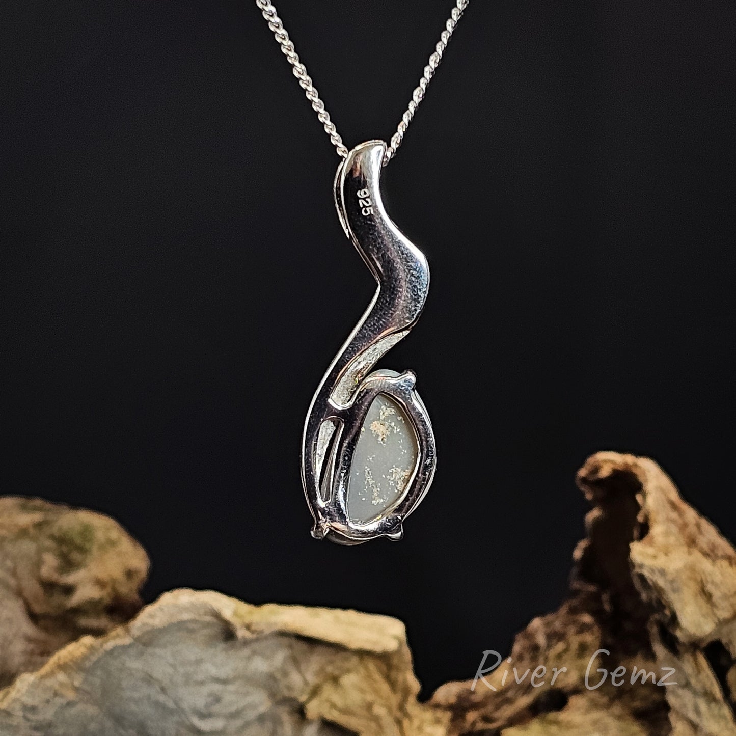 Rear view of silver necklace showing the grey base tone of the semi-black opal on a dark background