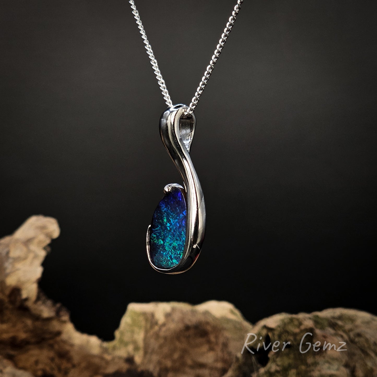 Silver pendant with blue gemstone on a dark background