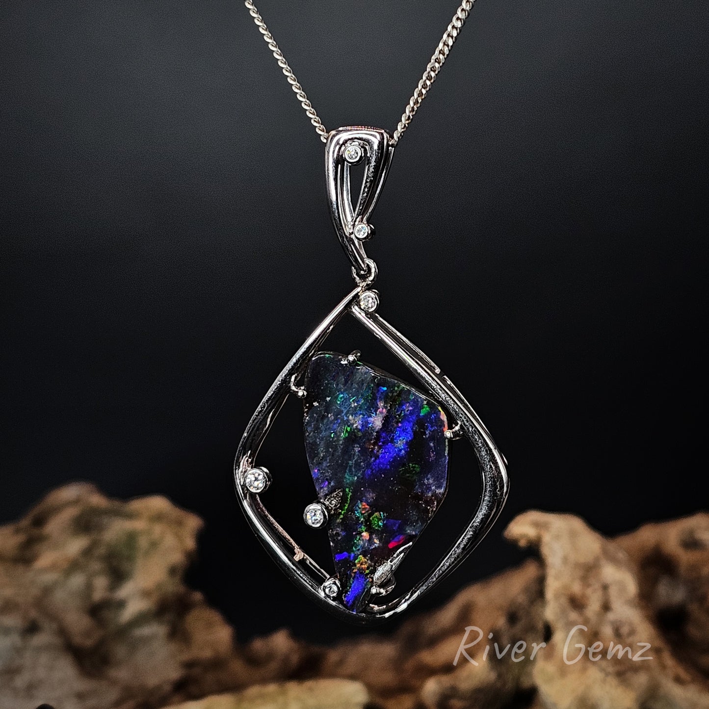 High grade white gold pendant with a colorful boulder opal on a dark background