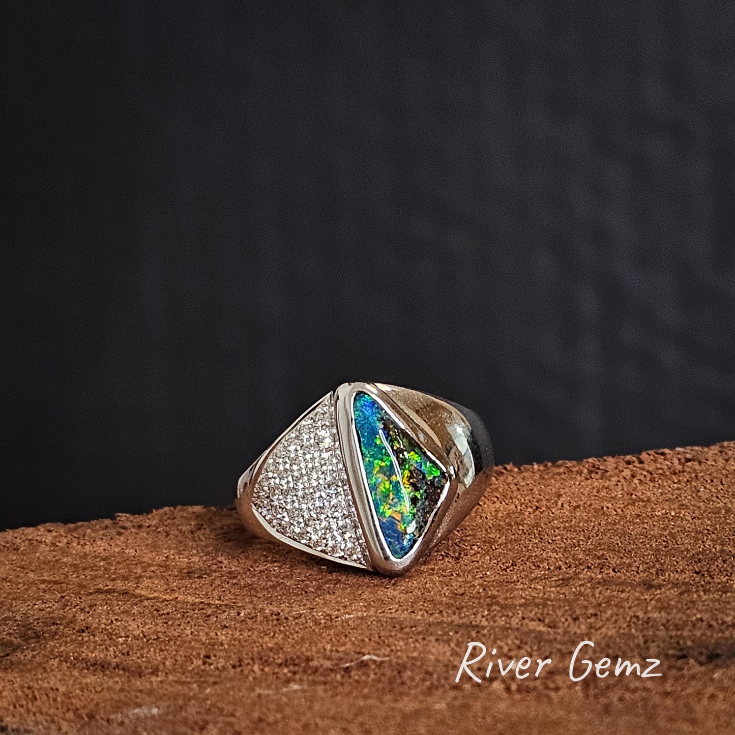 Large white gold ring with a triangle of diamonds and a multi-coloured triangular shaped boulder opal.