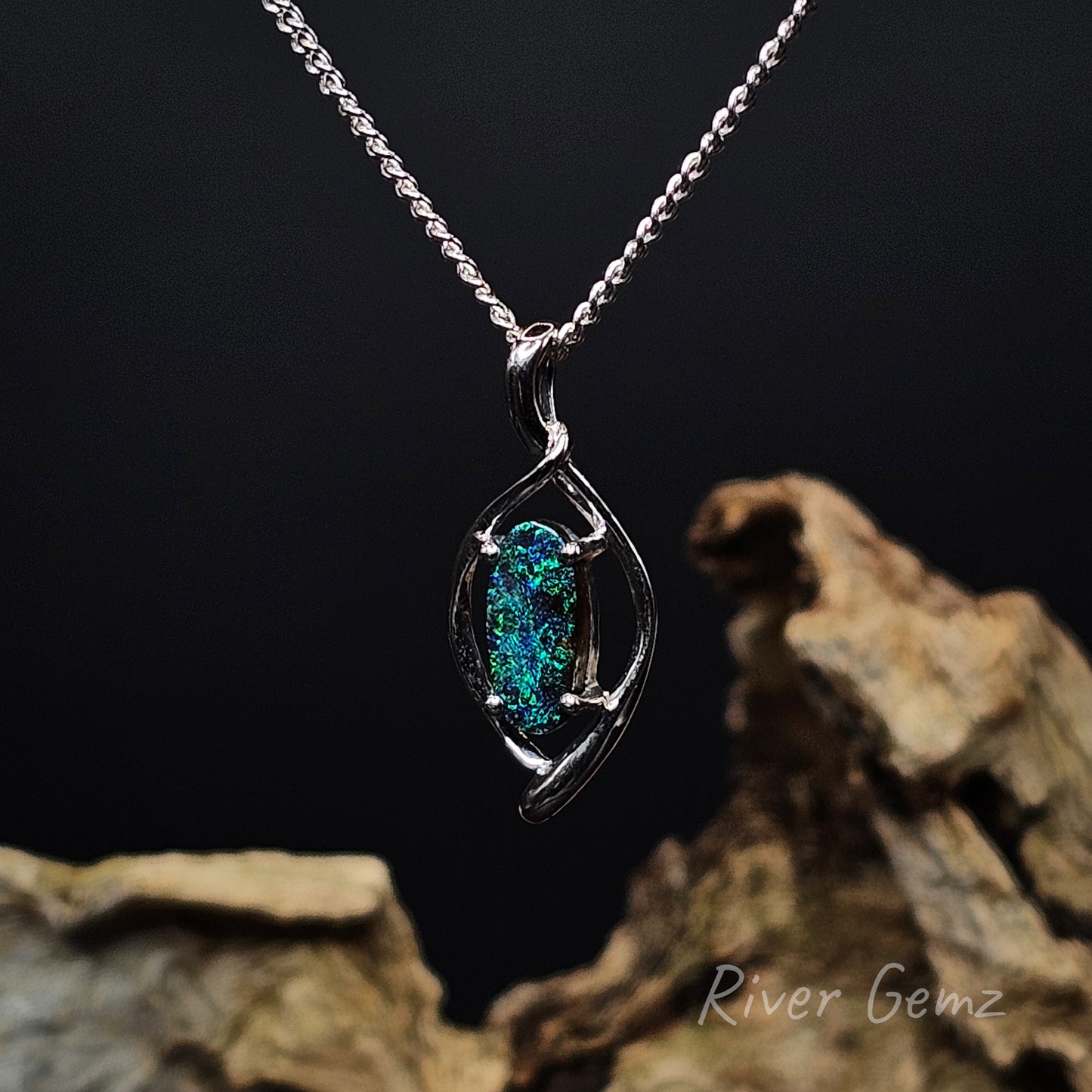 Silver pendant with a green gemstone on a dark background