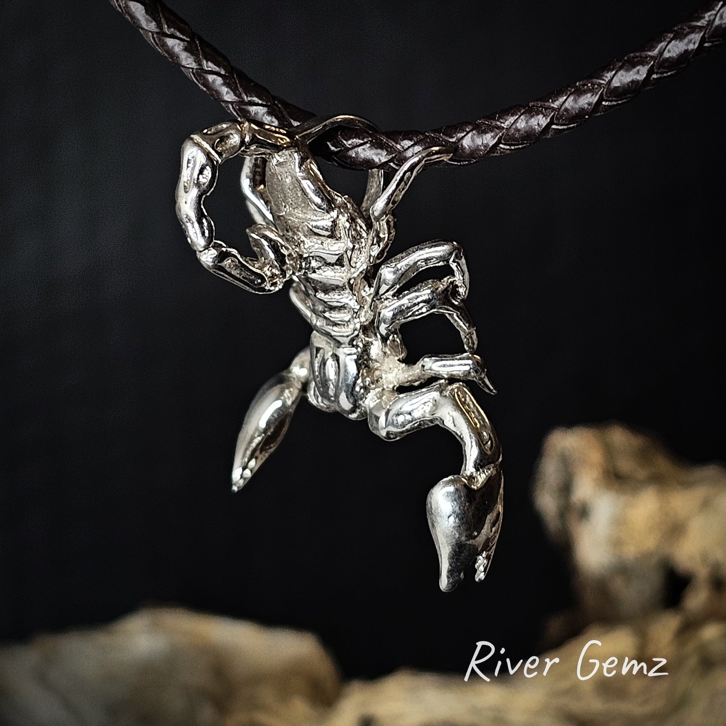 Silver scorpion pendant on a dark background with 'River Gemz' branding.