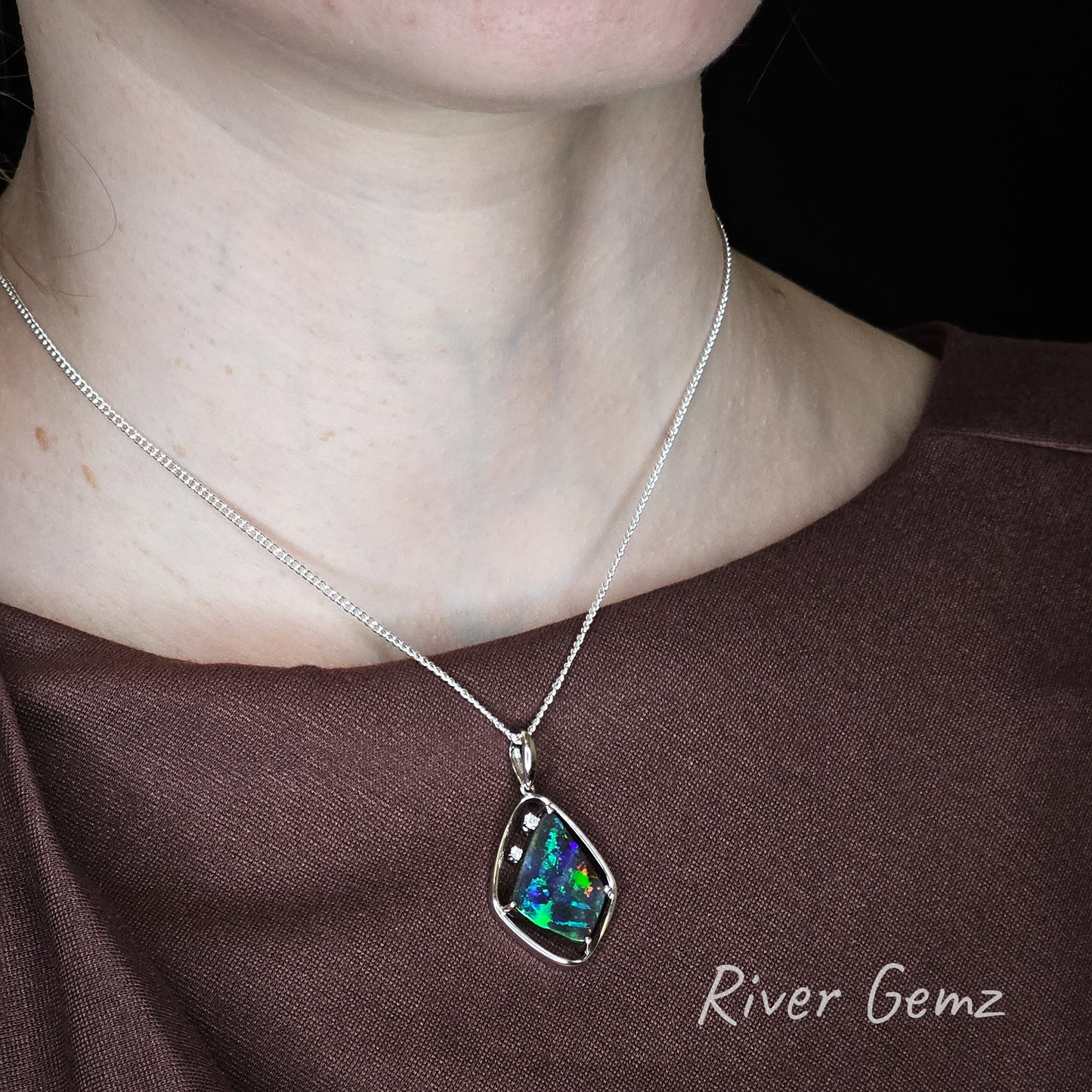 Necklace with a colorful pendant worn by a person, brand 'River Gemz' visible