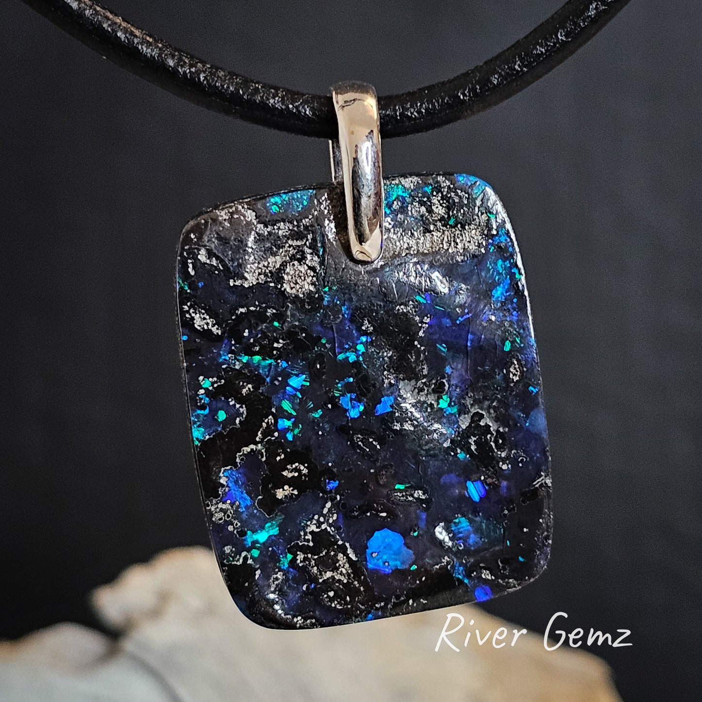 Dark blue, purple and bright green boulder opal pendant.