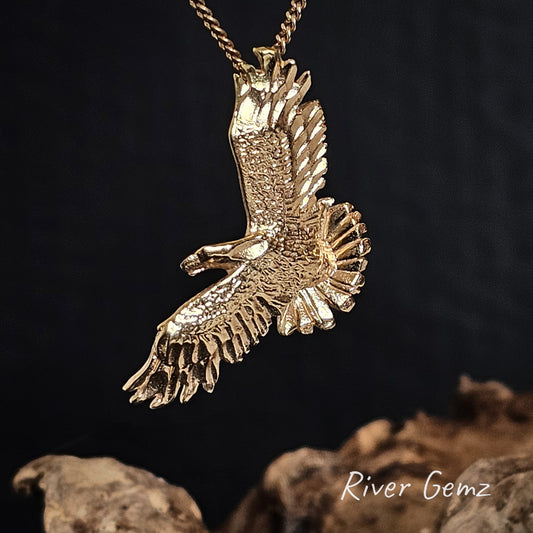 Gold eagle pendant on a chain against a dark background with 'River Gemz' branding.