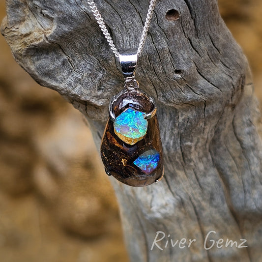 Two distinct areas of crystal opal encased in the ironstone host rock secured with 4 claws in the sterling silver setting. The opal is approximately tear-drop shaped.