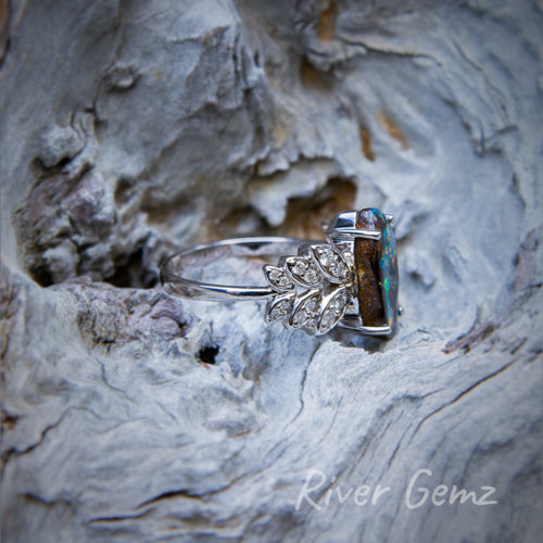 Side view showing the claw set opal and the leaf design on the side of the opal in the white gold ring.