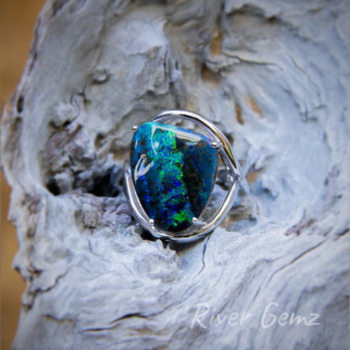 Triangular shaped dark blue green opal held securely by 4 claws in the white gold ring.