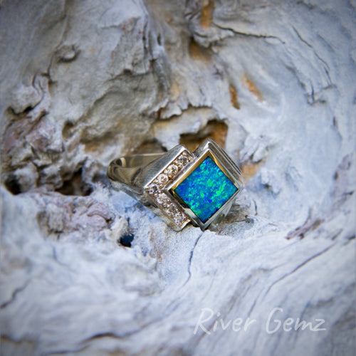 Dark blue and green diamond-shaped opal with two sides surrounded with diamonds in this Art-Deco type design of a white gold ring.