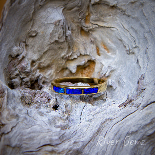 3 rectangular dark blue opals inlayed into a yellow gold ring.