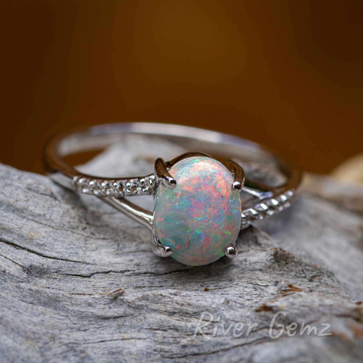 Oval shaped colourful opal held by 4 claws in the silver ring with 6 or 7 topaz stones each side of the opal. 