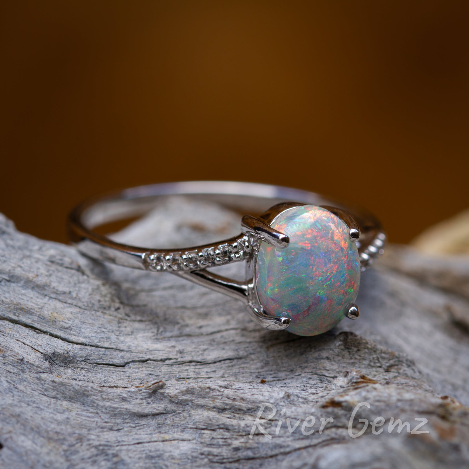 Slightly side on view of bright opal resting on light grey textured wood.