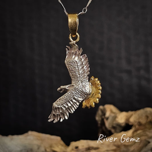 Silver eagle pendant with gold accents on a dark background