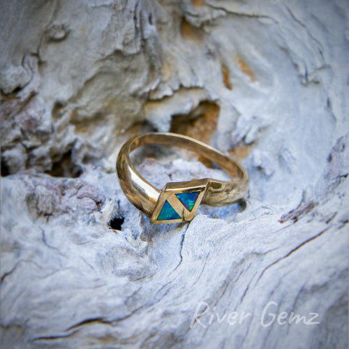 Two small triangular shaped dark green and blue opals co-joined in a yellow gold inlay ring.