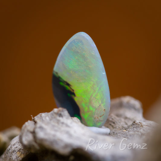 Free form cut opal with one portion black potch and the rest green crystal.