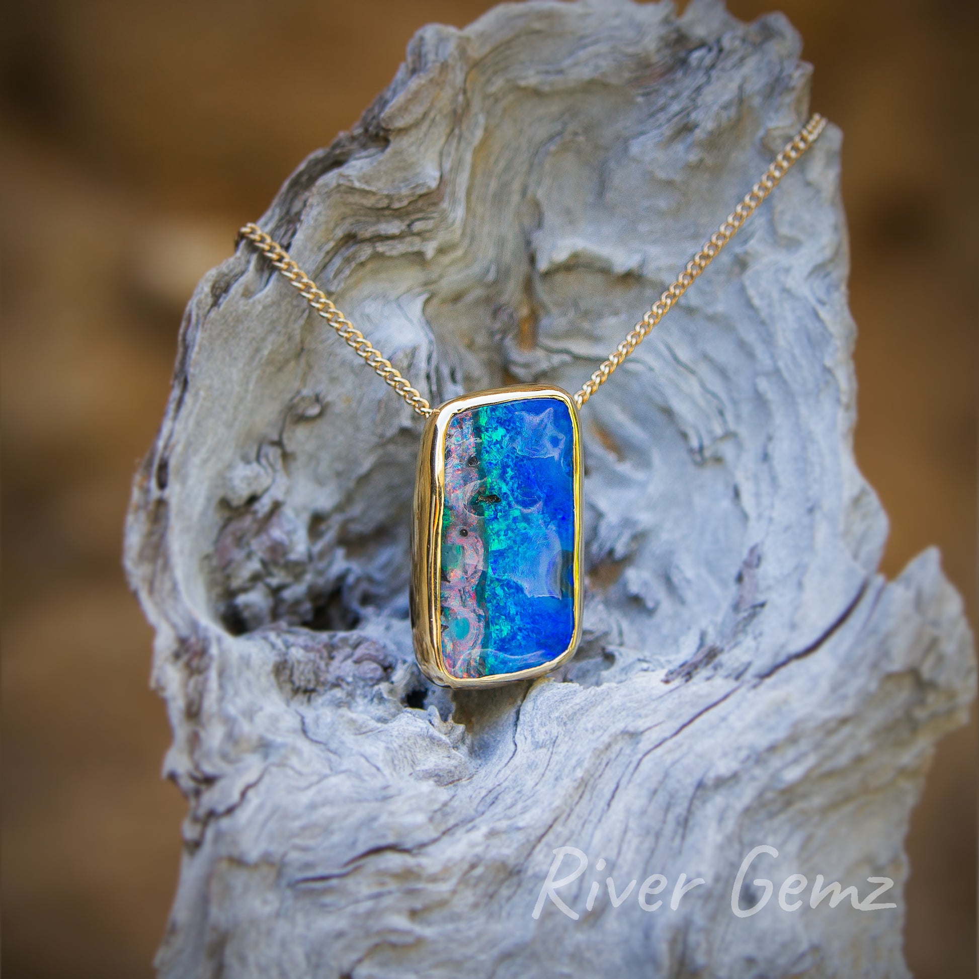 Amazing degree of polish achieved by the lapidarist on this quadrilateral shaped multi-coloured opal. Pendant hangs on a light-grey grained piece of driftwood.