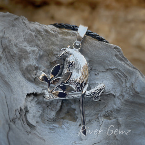 Silver necklace with Tree kangaroo sitting on a branch which includes 6 leaves.