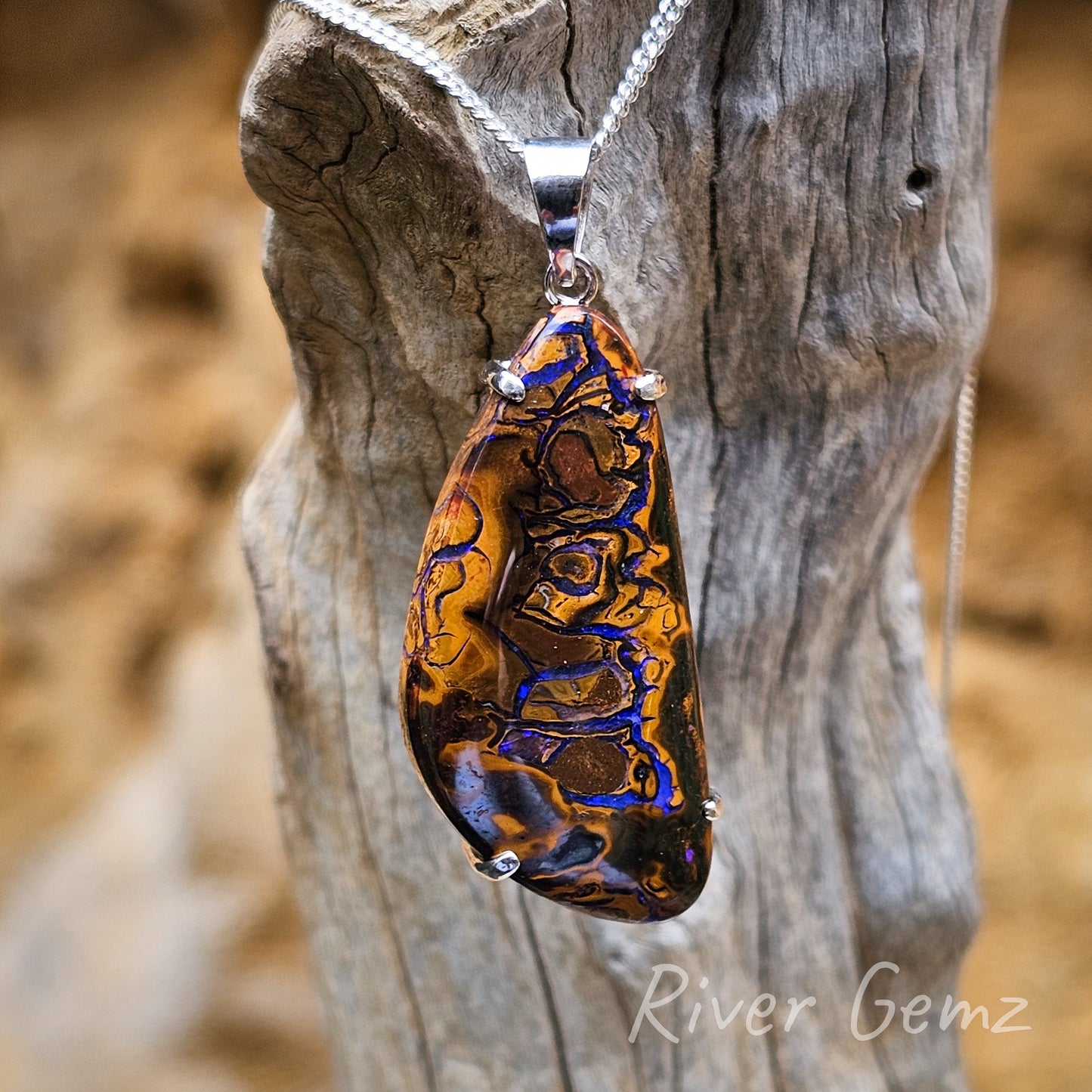 Blue/purple swirls of colour of opal embedded in the ironstone host rock. Two tone browns in the matrix opal contrasted against the light coloured drift wood background.