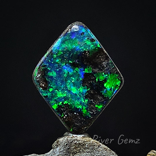 First of 2 photos shows a front view of the opal. Blue/green colours in large spheres with the ironstone base of the boulder opal. Black background used in the photo.