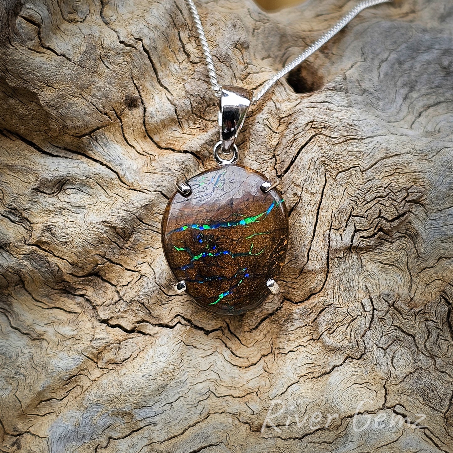 Close up photo of the pendant. The opal is secured in the setting with 4 claws and a tapered bail which the silver chain passes through completing the necklace.