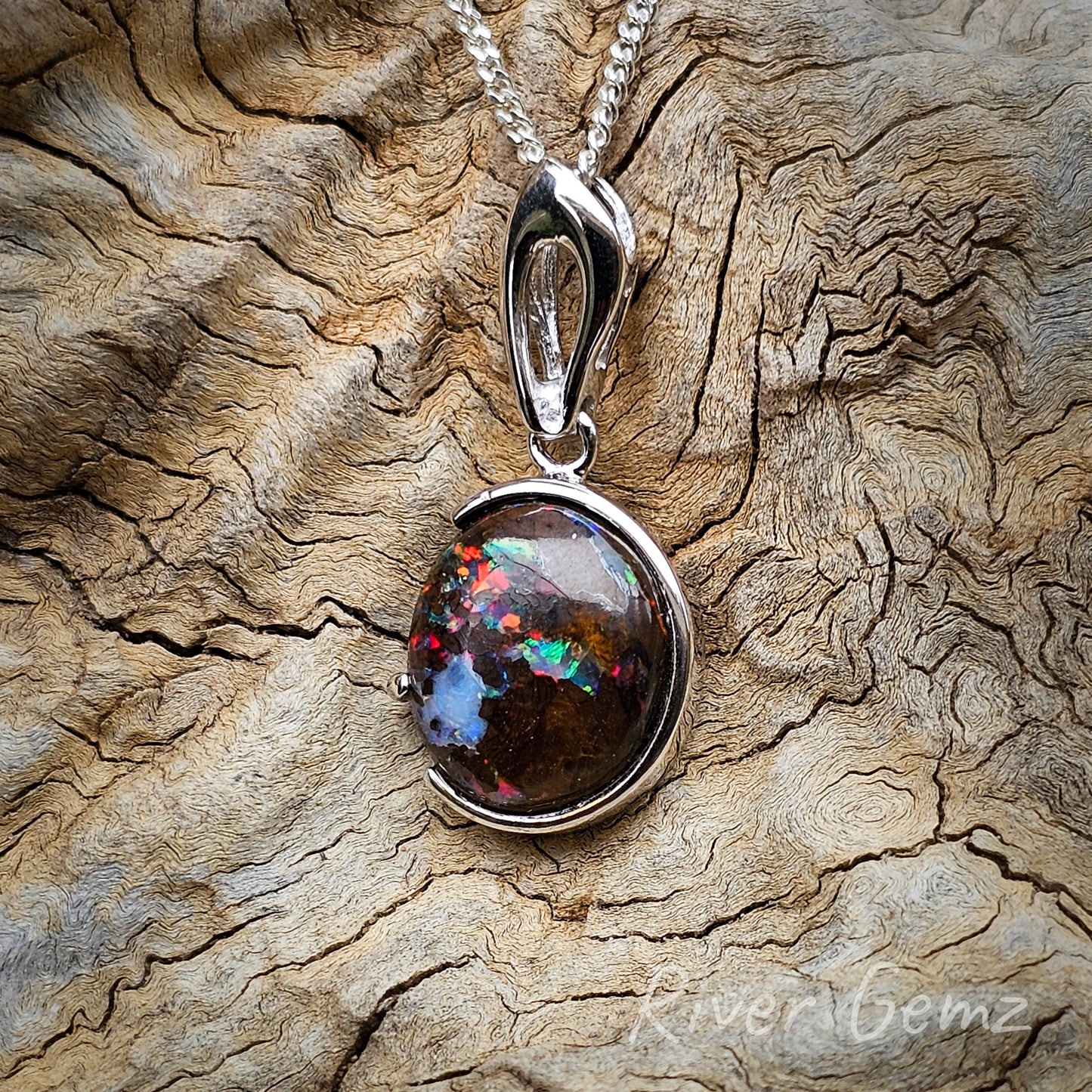 Almost circular shaped multi-coloured matrix opal with a reverse C besel and 1 claw securing the opal in the pendant. Modern style rabbit's ear bail half the size of the pendant.