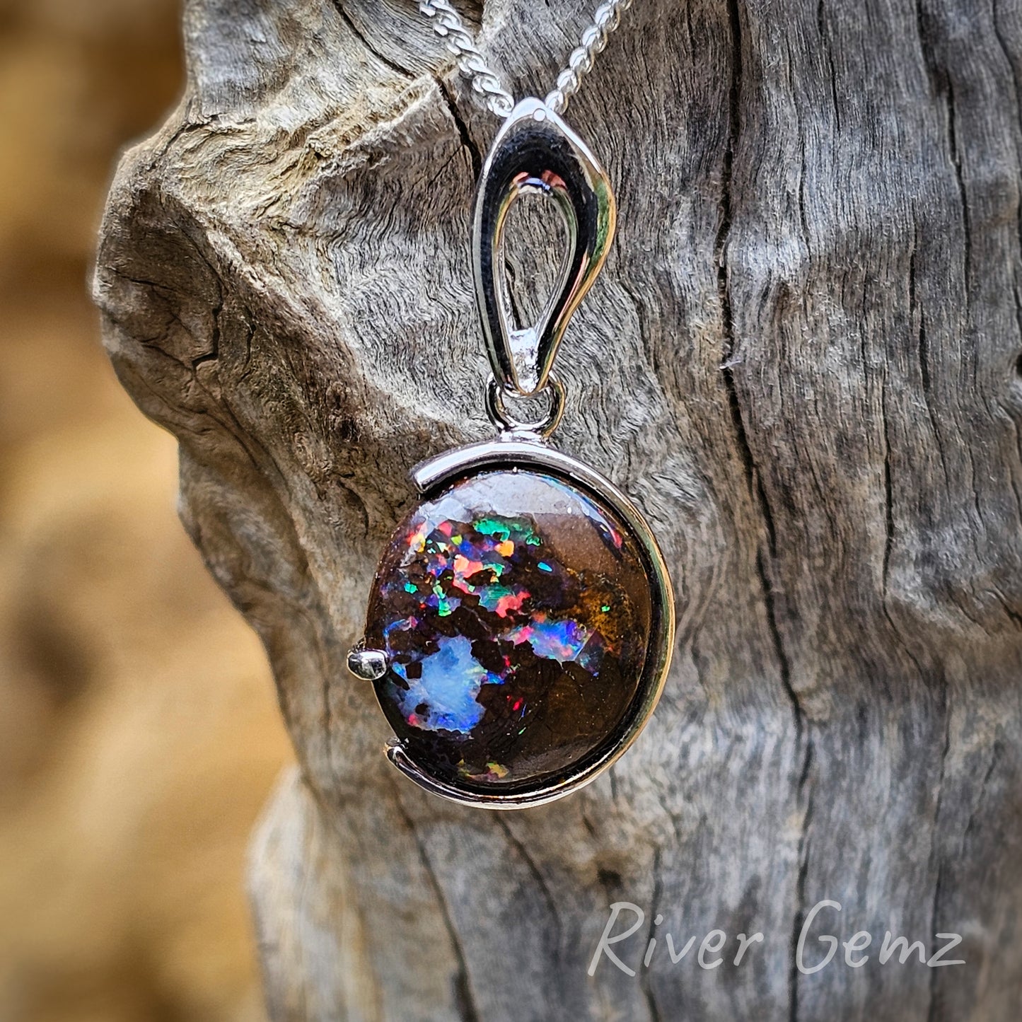 Splotches of colour resemble a modern piece of artwork. Dark brown tones of the ironstone host rock stand out against the light greys of the driftwood from which the pendant hangs.