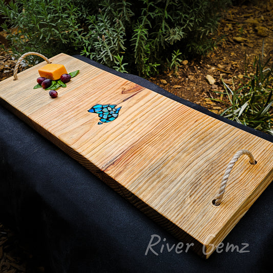 First of three photos. Full length of the graze board is shown diagonally across the image. The wood grain is vertical. Some cheese and grapes are added for visual appeal. Rope handles are attached via two drilled holes through the top of the board.