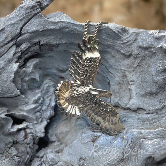 Gold pendant depicting an eagle with wings and tail feathers fully expanded.