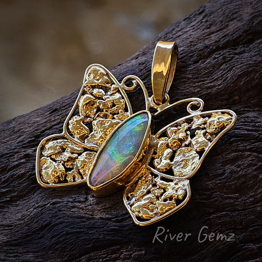 Irregular oval shaped opal forms the butterfly body and multiple nuggets in each wing. Lots of gold visible contrasted against the timber background which the butterfly is resting on at a slight angle in this photo.