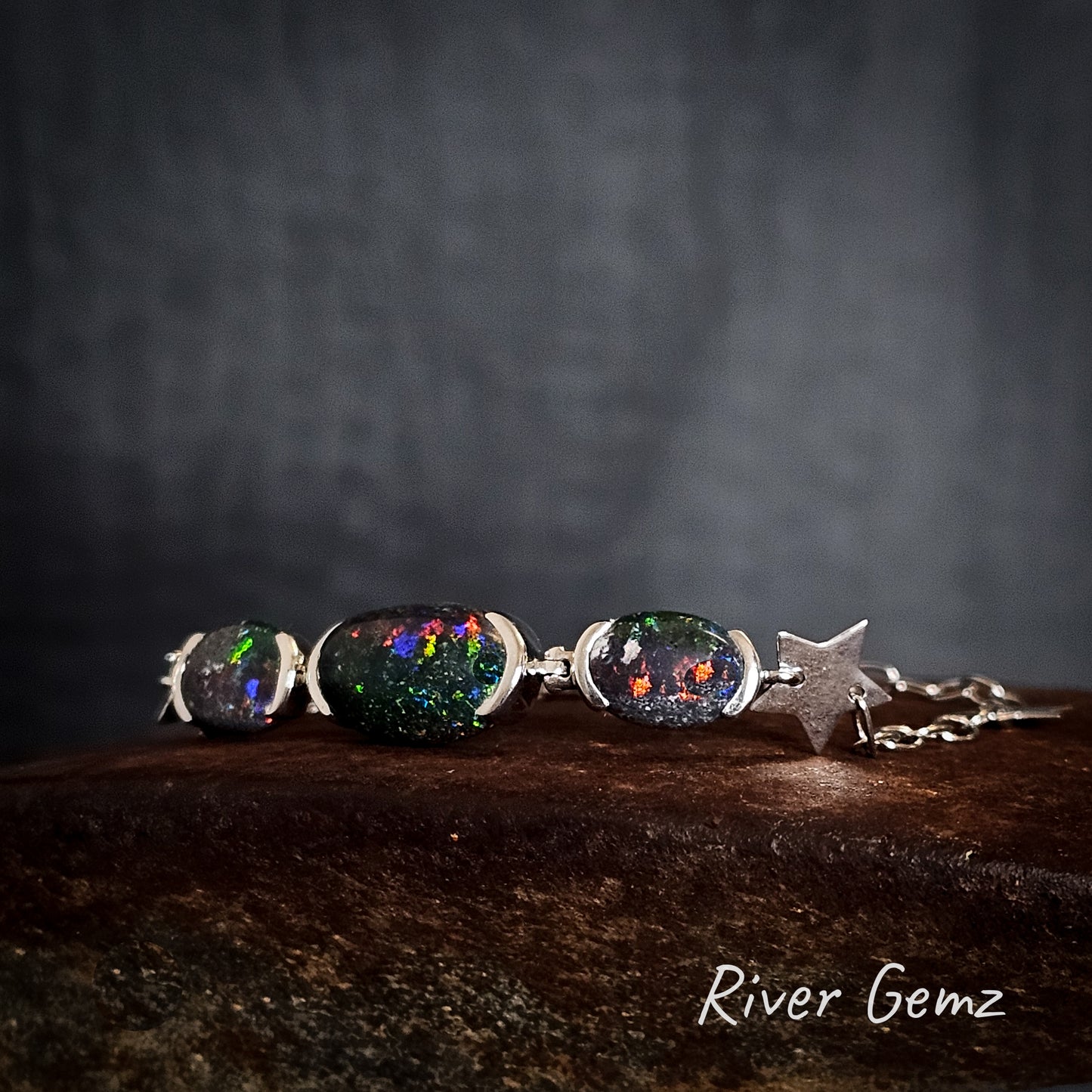 Sterling silver bracelet with multi-coloured opals on a dark background, featuring the brand 'River Gemz'.