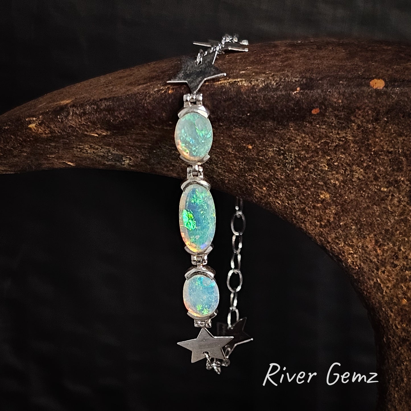 Three green light opals set in sterling silver bracelet with stars part of the chain link.