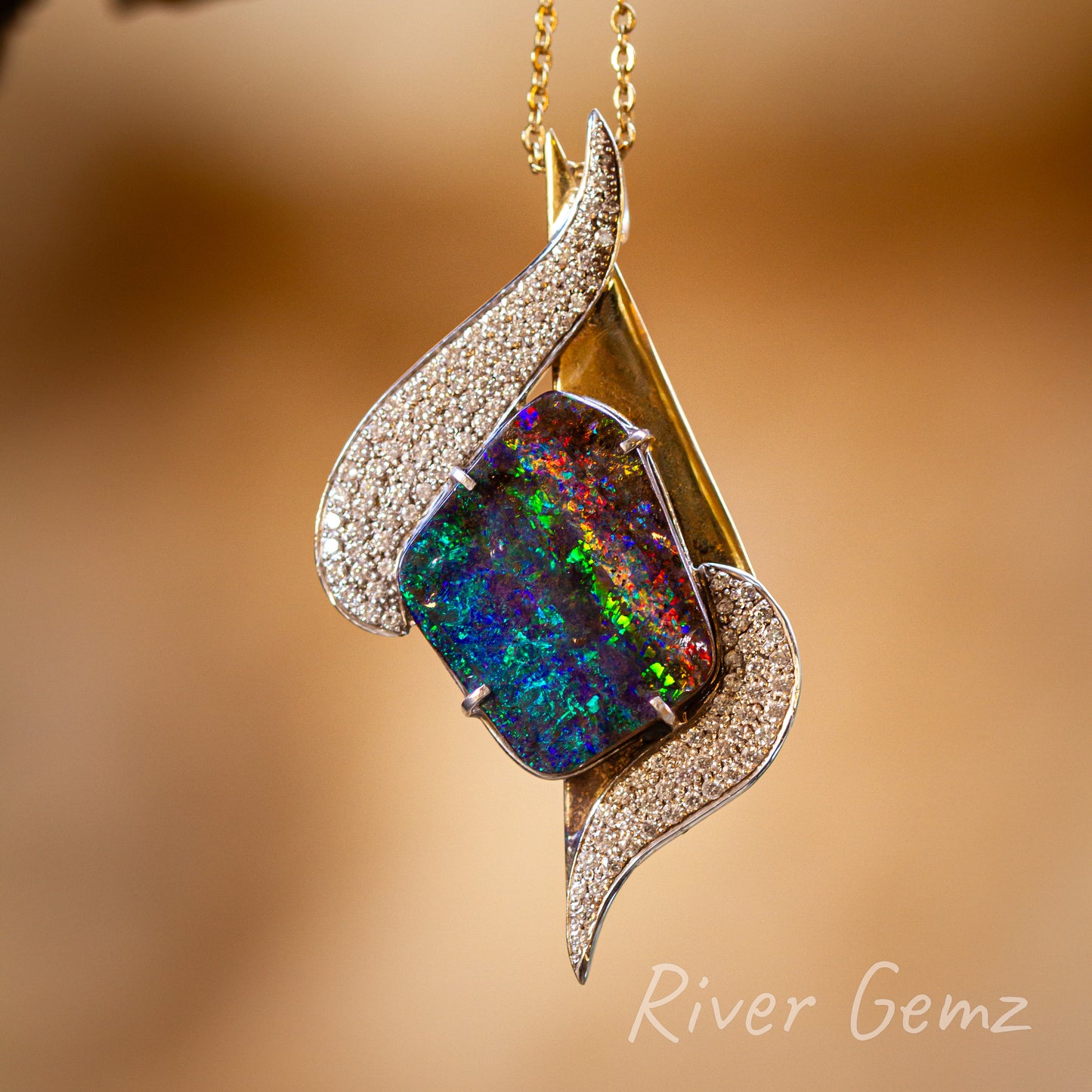 Free-form cut four sided boulder opal with a rainbow of colours held securely by 4 claws in the 18K gold pendant with 72 diamonds in two swirls above and below the opal. Chain passes through the gold setting and so no separate bail.