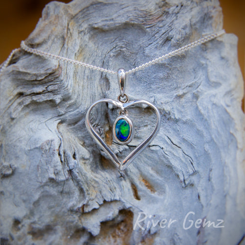 Calibrated, oval-shaped, blue-green opal besel set in the centre of a heart shaped pendant.