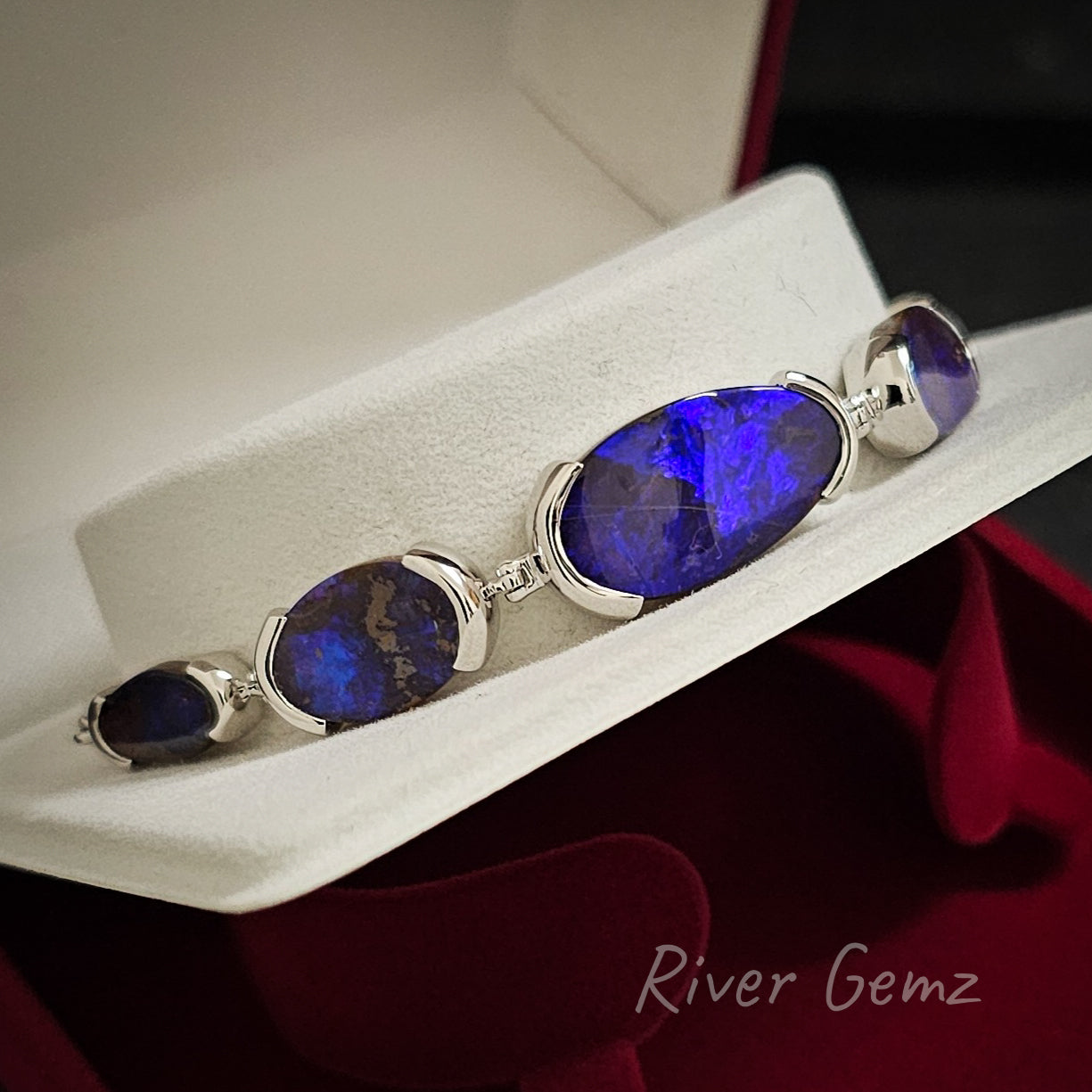 4 of the 5 vivid blue boulder opals are visible in this side view of the sterling silver bracelet.