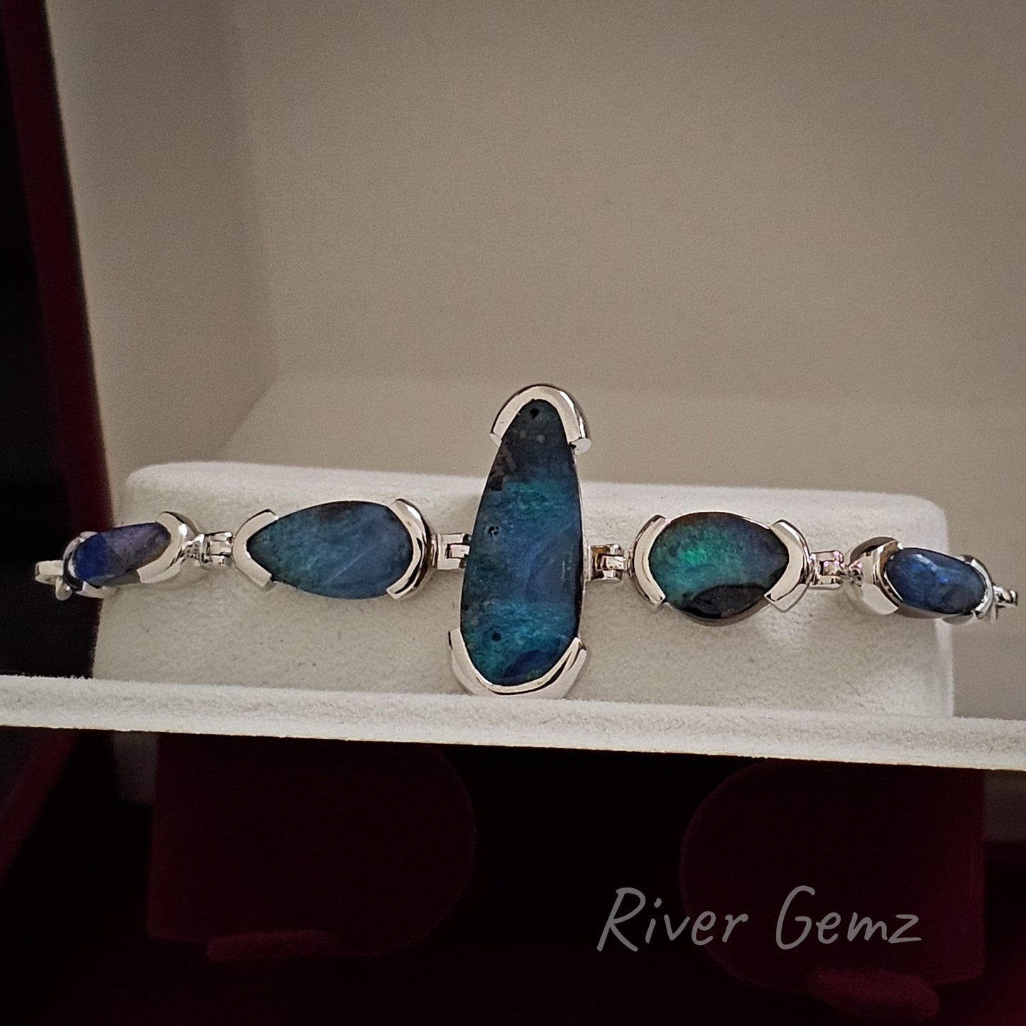 5 solid green blue opals in a sterling silver bracelet shown in a bracelet box with a white insert.