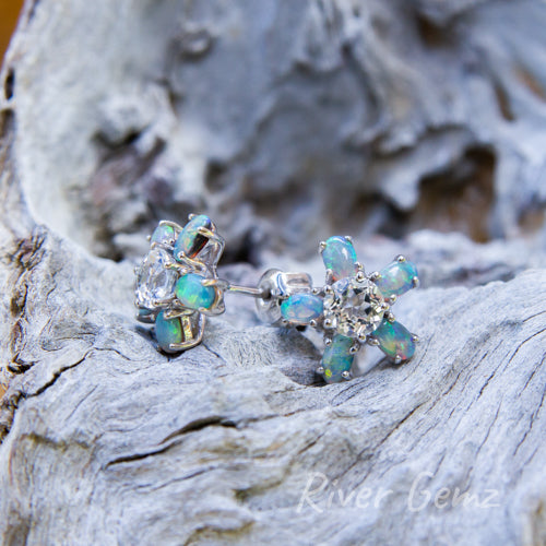 5 oval shaped blue-green light opals surround a round white topaz gemstone in each silver earring in a floral design.