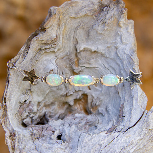 Three oval-shaped light opals in a modern designed silver bracelet with chain links.